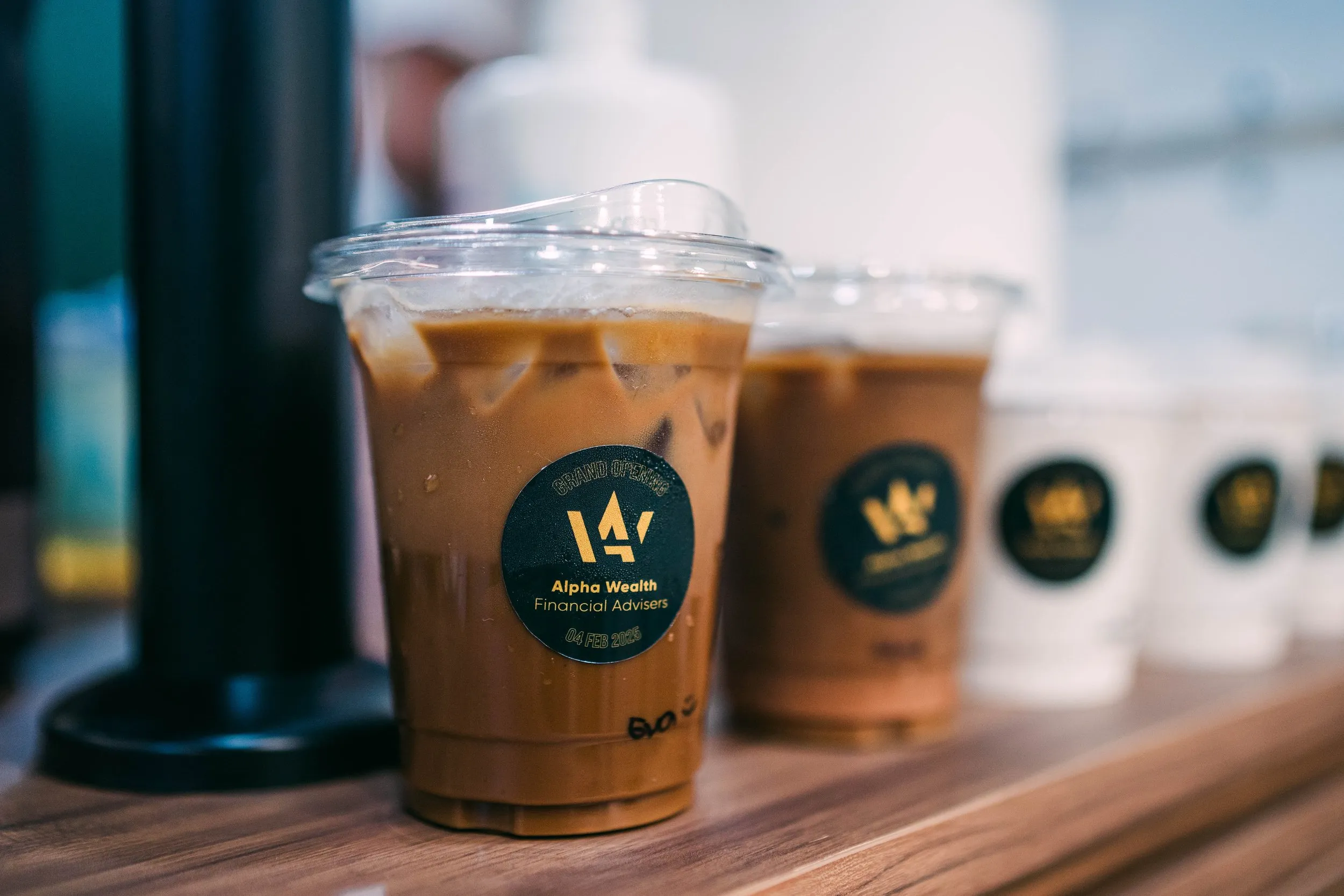 Multiple cups of iced coffee with dark labels on a wooden surface