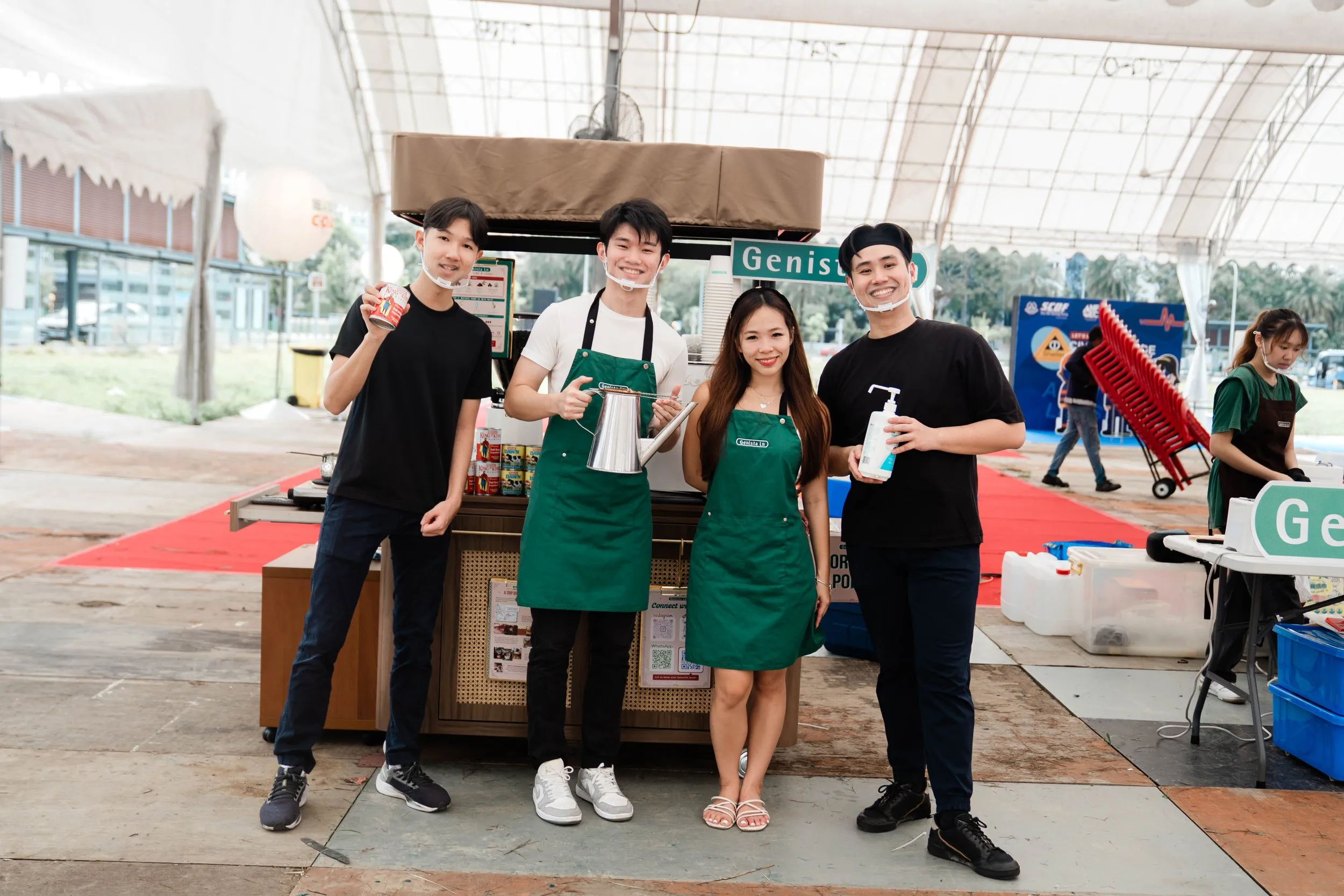 Genista Ln crew smiling beside their kopi cart at an outdoor community event