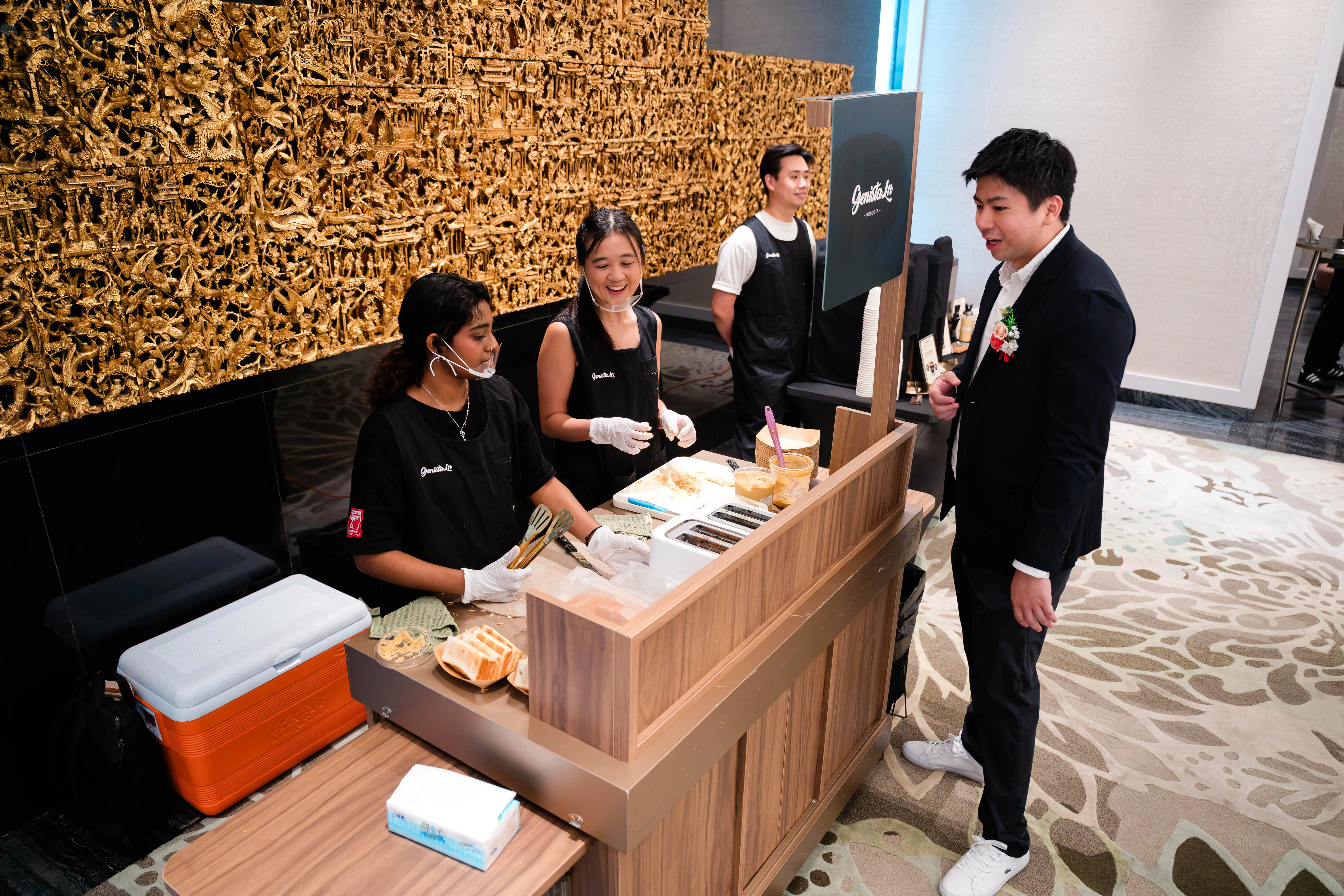 Genista Ln crew preparing kaya toast at the cart during Jarryl & Elleze's wedding, the groom watching from beside the counter
