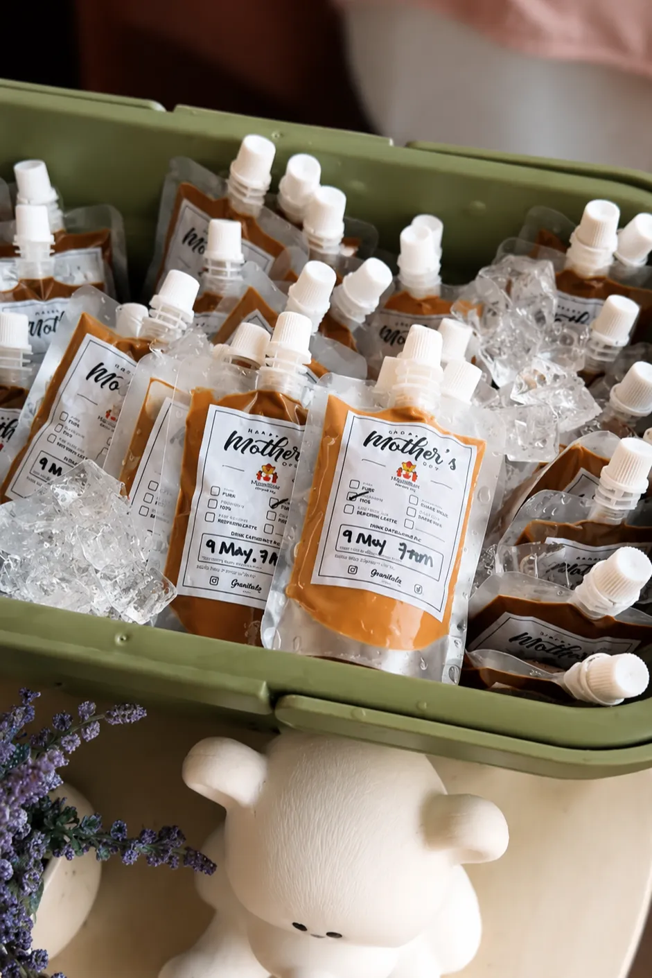 Genista Ln kopi pouches packed upright on ice in a cool box, each label ticked and hand-dated, with a sprig of lavender and a small white bear figurine in front of it